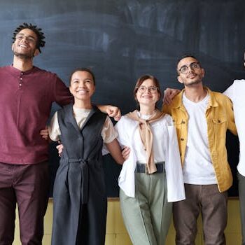 A diverse group of colleagues joyfully embracing in an office setting, showcasing team spirit.
