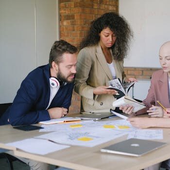 Group of multiracial businesspeople speaking and sharing data about project and analyzing reports in notebooks at table in office